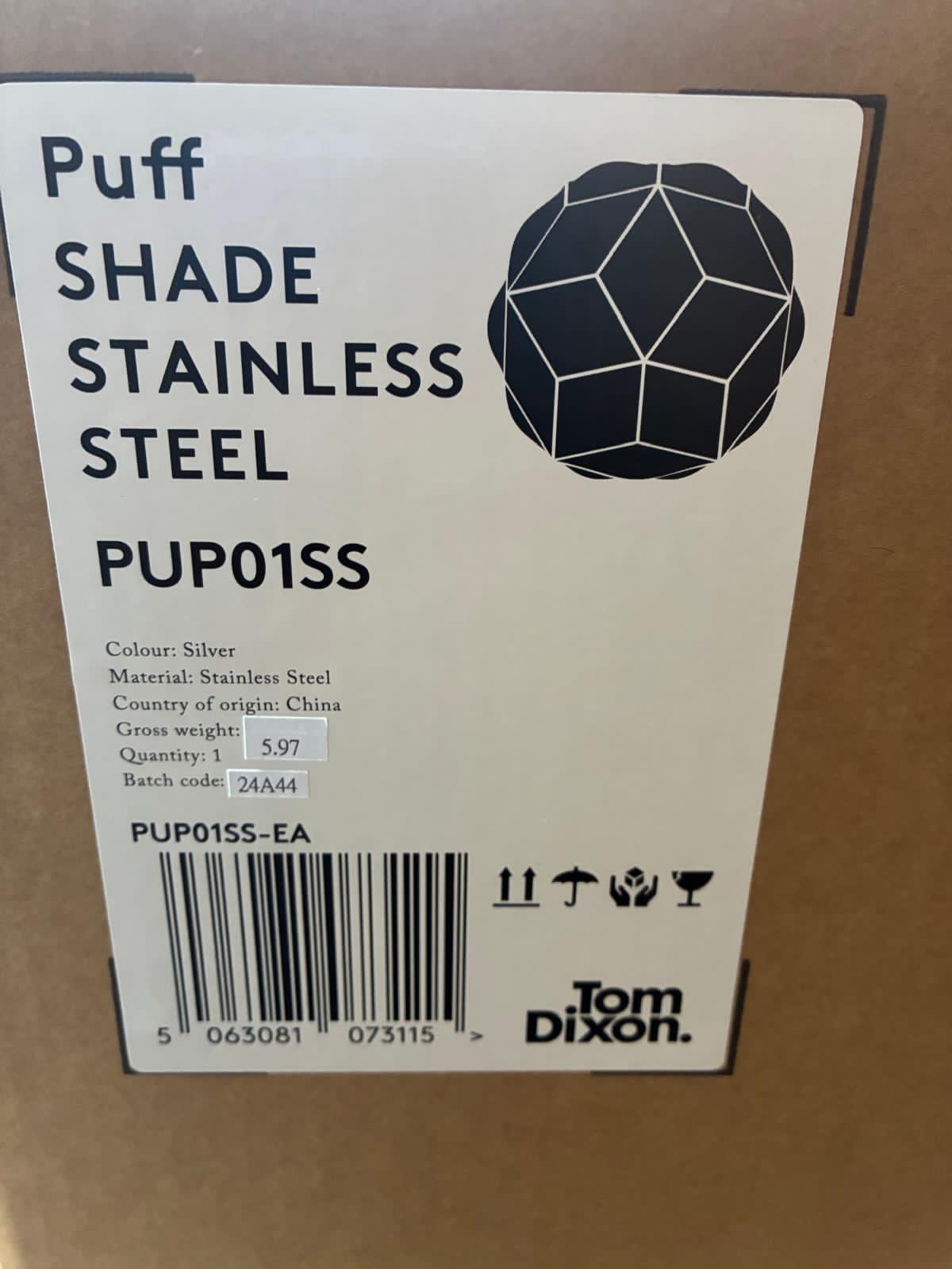 Modern Tom Dixon Puff Pendant Light in polished stainless steel with a black fabric cable, showing its unique 'inflated' geometric shade and reflective facets." Heal's and Nest often highlight its light-scattering properties.