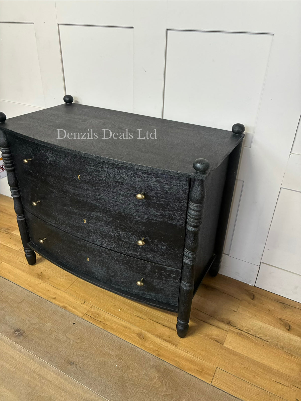 The black Anthropologie Spindle Three-Drawer Dresser styled in a modern bedroom, showcasing its graphic quality, dark wood finish, and distinctive architectural spindle legs that provide an open, lightweight feel."