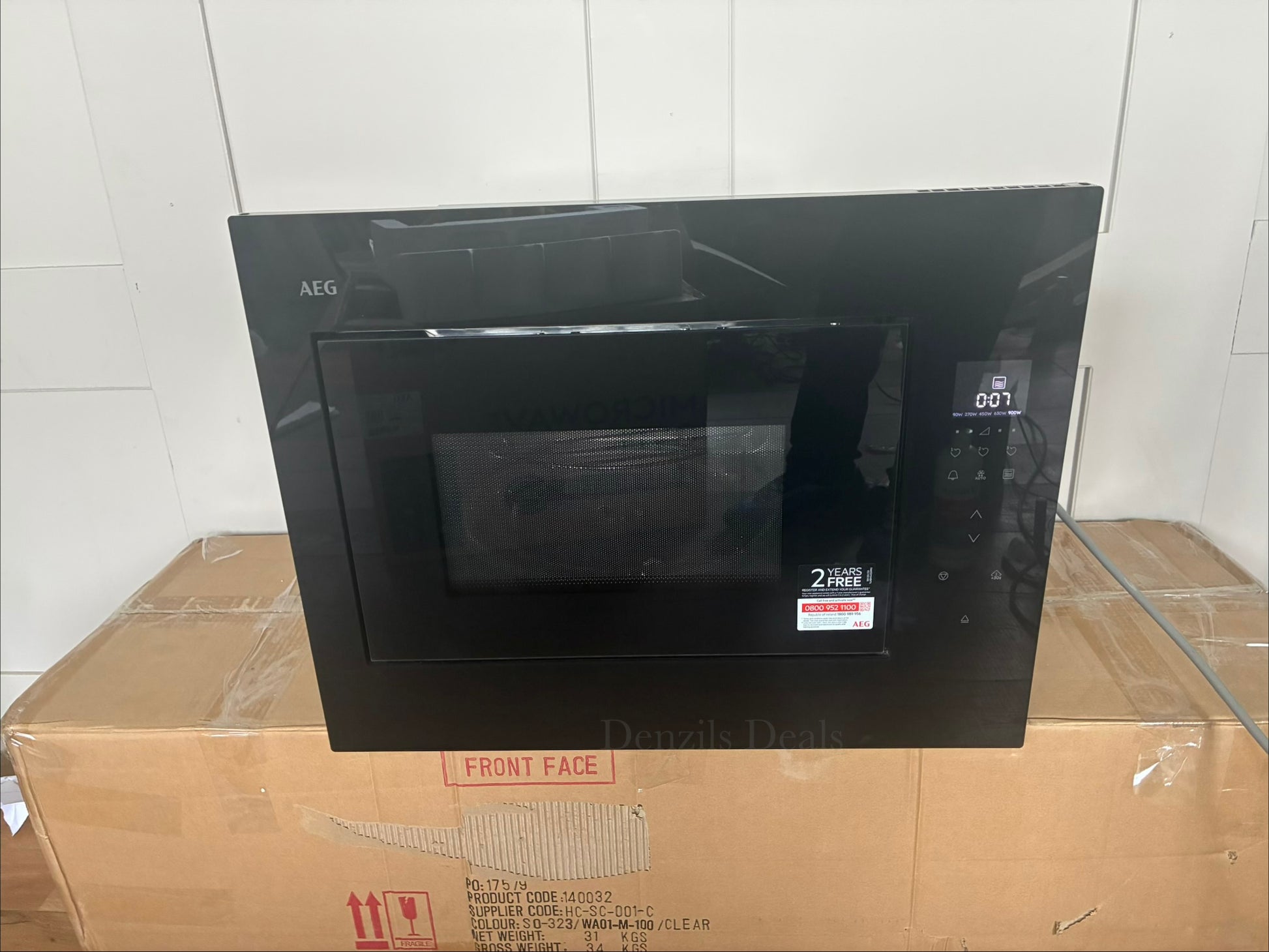 Front view of the AEG OB6SM261UB 6000 Series built-in microwave oven, featuring a sleek, minimalist all-gloss black glass finish. The front panel includes a horizontal LED digital display and touch-sensor controls on the right side, with an invisible push-to-open door mechanism