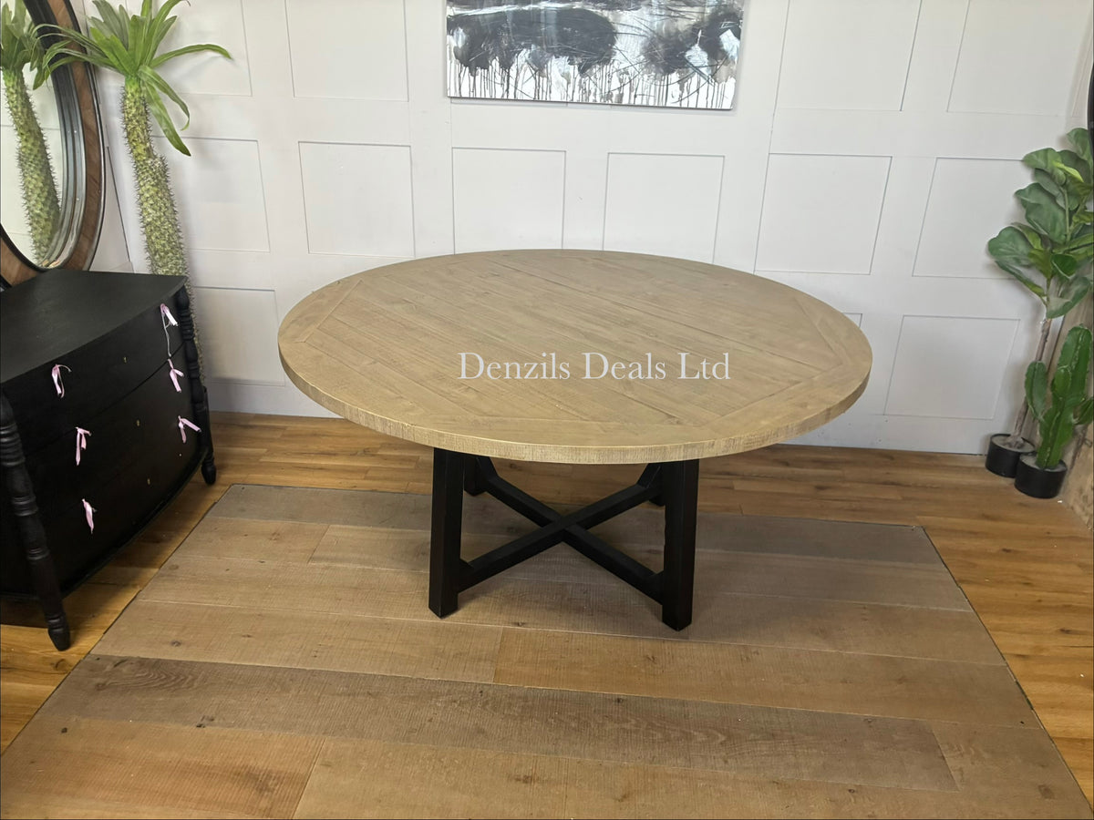 A 160cm round dining table featuring a natural pine tabletop with a visible wood patina and cross-shaped black metal legs.