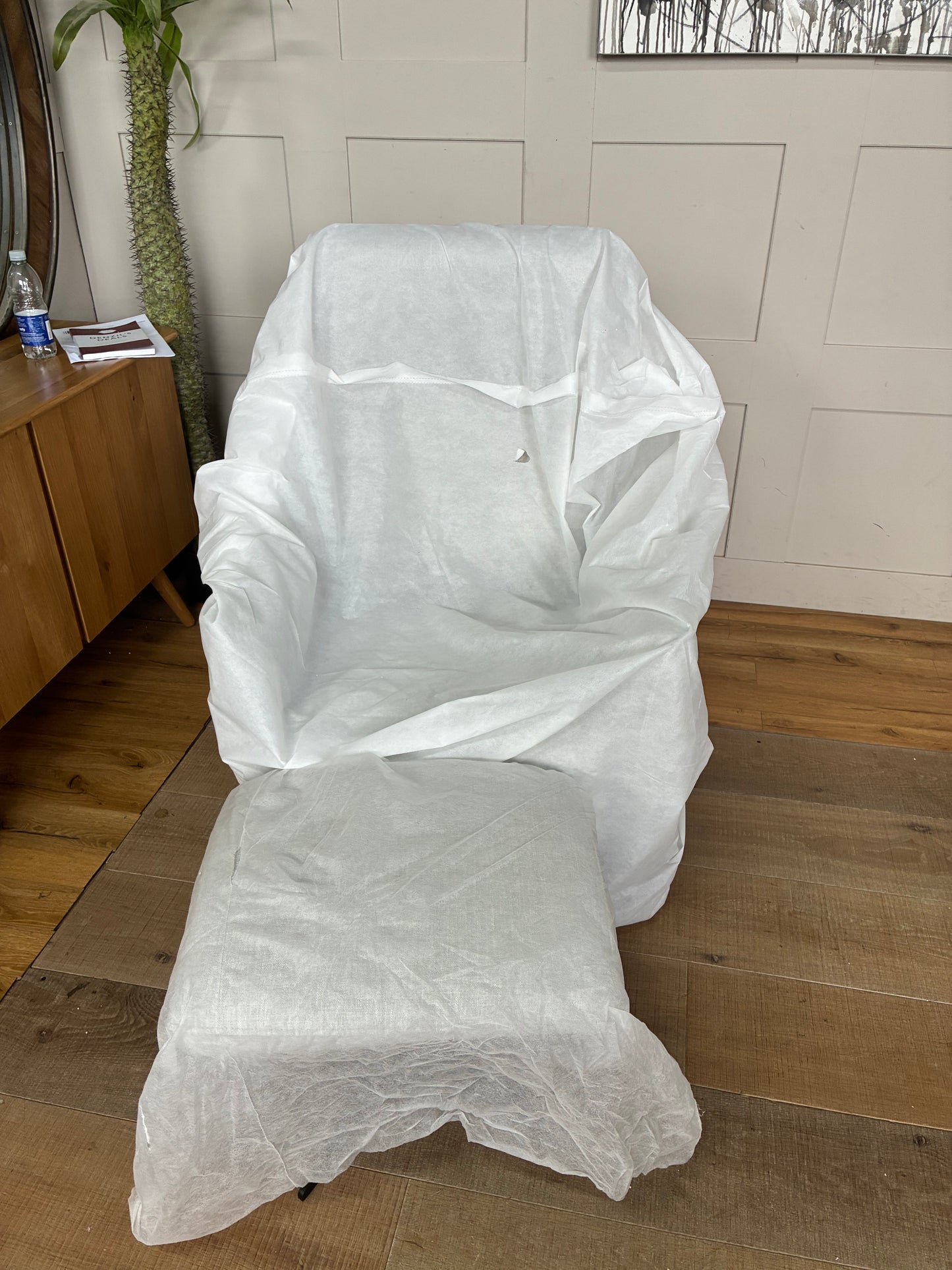 A John Lewis contemporary ergonomic armchair and footstool set featuring a plush, high-back silhouette covered in textured light grey chenille upholstery. The set is elevated on sleek, angular black metal legs, showcasing a comfortable, modern look for a living room or study.