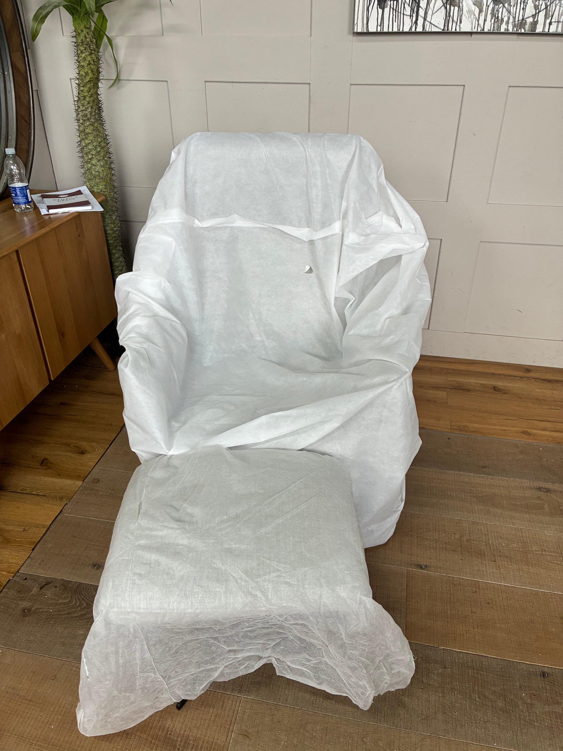 A John Lewis contemporary ergonomic armchair and footstool set featuring a plush, high-back silhouette covered in textured light grey chenille upholstery. The set is elevated on sleek, angular black metal legs, showcasing a comfortable, modern look for a living room or study.