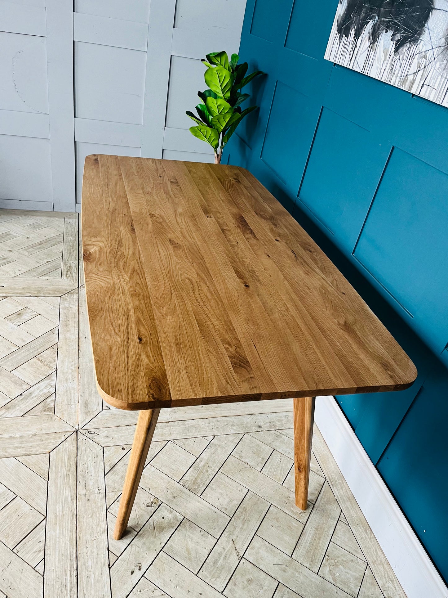 A Scandi-inspired minimalist 4-seater dining table by John Lewis, crafted from American oak wood with a visible natural grain, an oiled finish, and tapered legs.