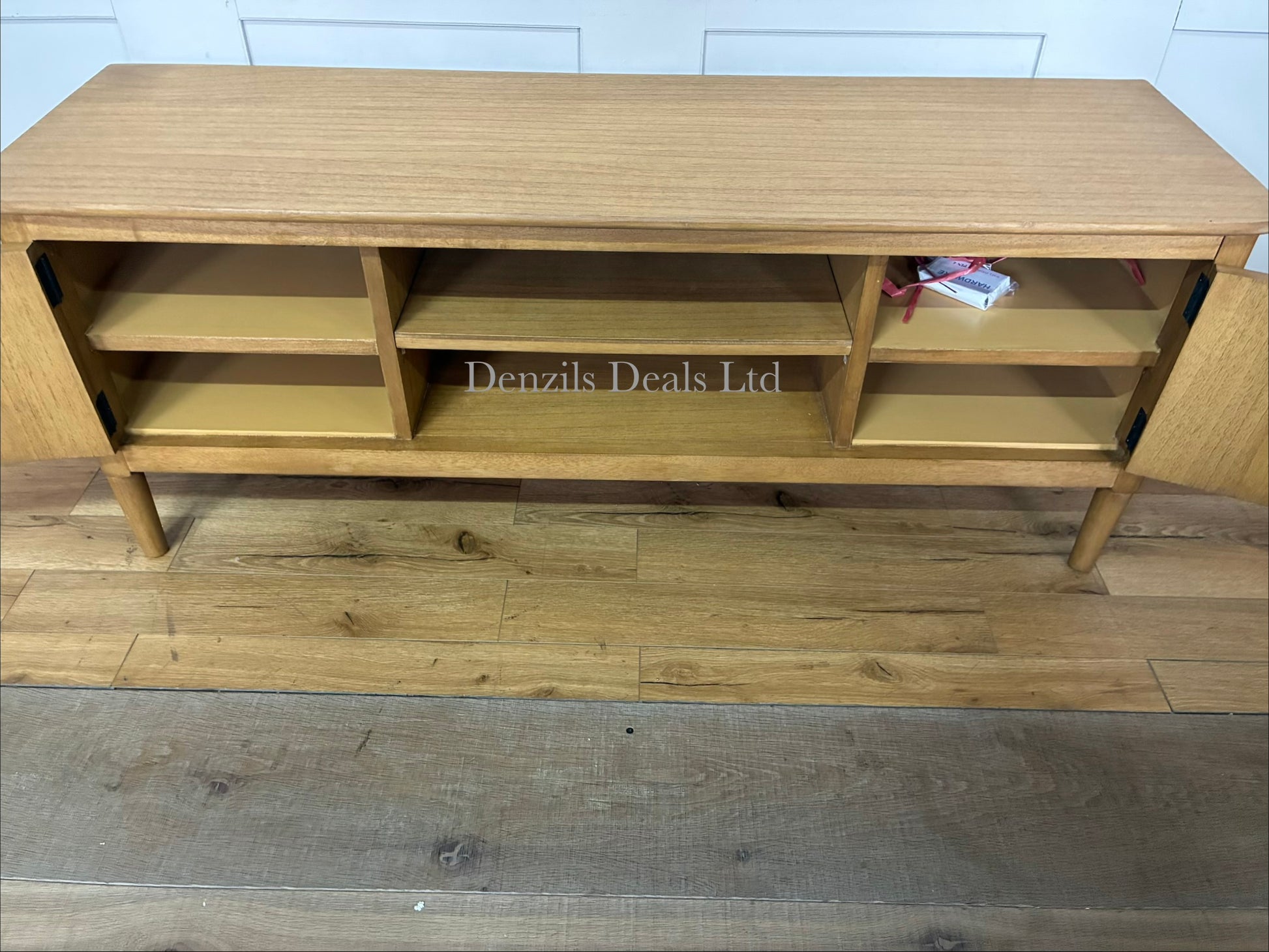 A Scandinavian-style solid oak media unit supporting a television in a modern, neutrally decorated living room