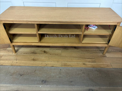 A Scandinavian-style solid oak media unit supporting a television in a modern, neutrally decorated living room