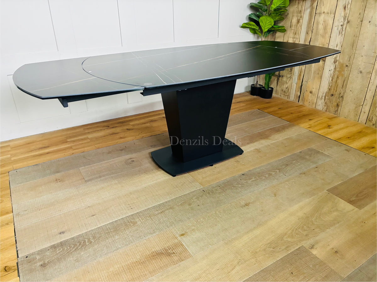 A black ceramic marble-effect dining table extending from 150cm to 220cm, showing the rotating mechanism that reveals side extension leaves to comfortably seat up to 8 people