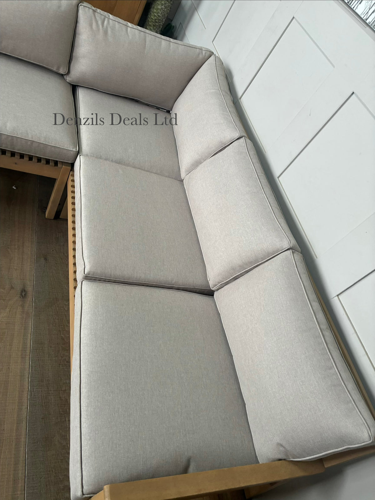 A contemporary John Lewis Mona 4-seater corner garden sofa made from natural-finish acacia wood with cream-coloured seat and back cushions.