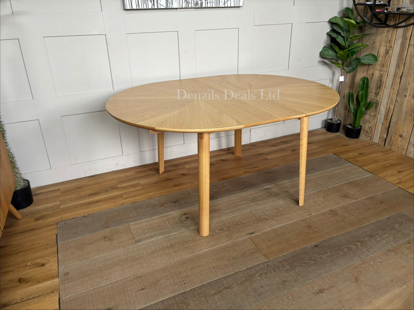 A contemporary John Lewis Notch round dining table made from natural oak, featuring a distinctive starburst veneer pattern on its circular top and sturdy, clean-lined legs. The table expands from a 4-seater to a 6-seater using a central fold-out extension leaf."