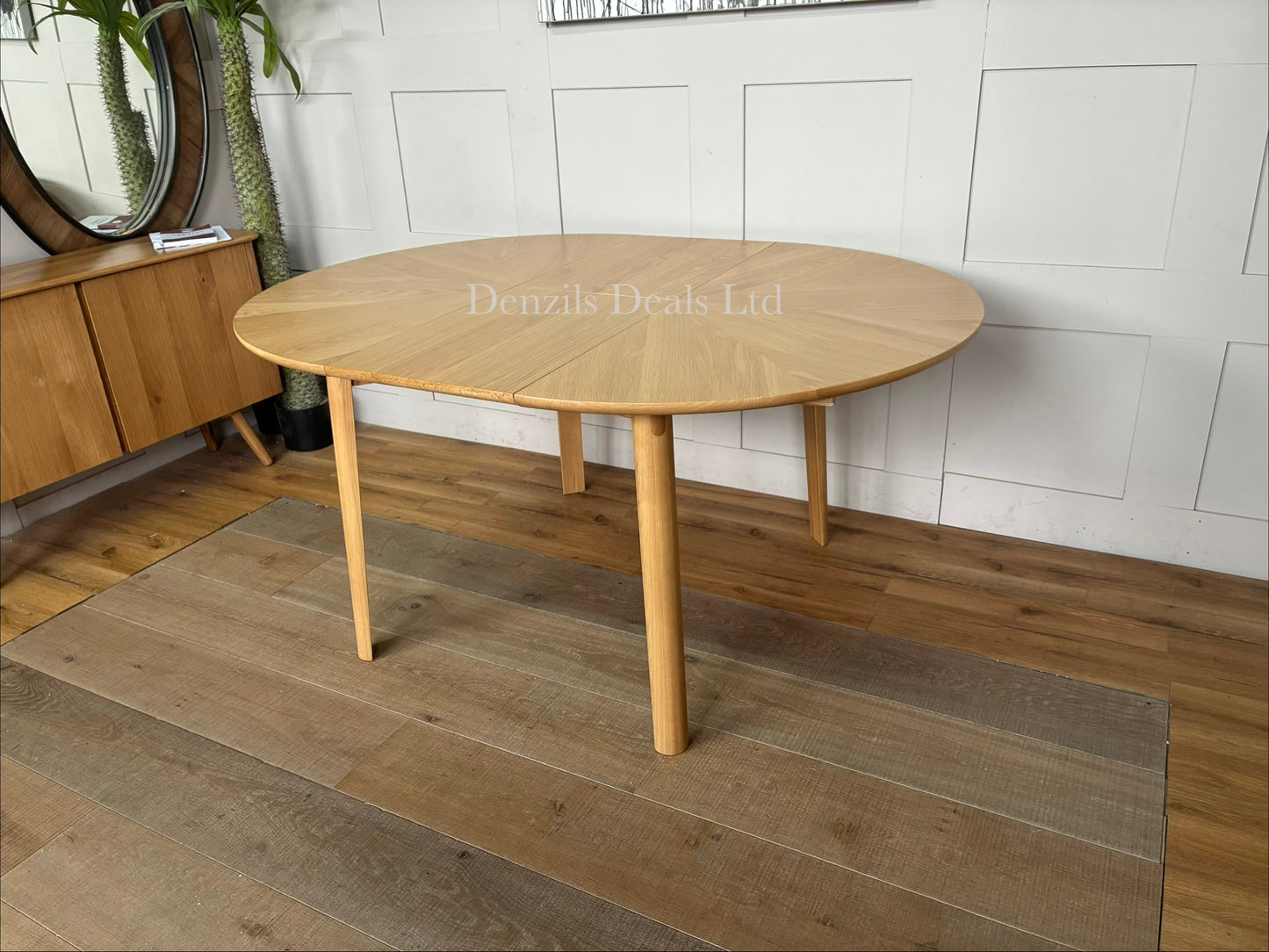 A contemporary John Lewis Notch round dining table made from natural oak, featuring a distinctive starburst veneer pattern on its circular top and sturdy, clean-lined legs. The table expands from a 4-seater to a 6-seater using a central fold-out extension leaf."