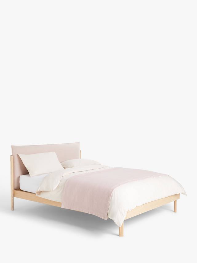 A contemporary double bed with a natural wood frame and grey cushioned headboard, styled in a minimalist modern bedroom with white bedding.