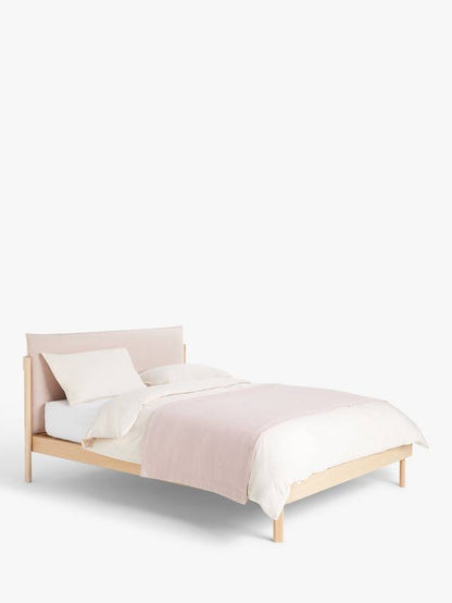 A contemporary double bed with a natural wood frame and grey cushioned headboard, styled in a minimalist modern bedroom with white bedding.