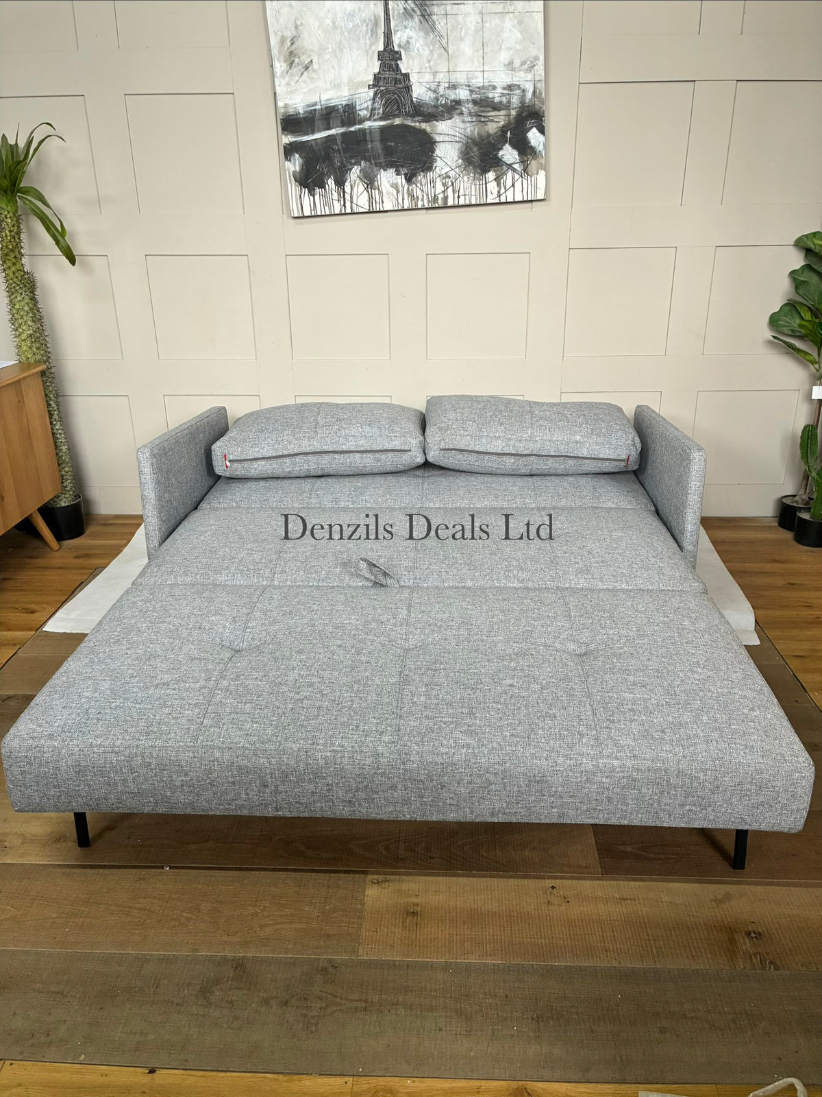 A contemporary living room featuring the compact Innovation Living Cubed 160 Sofa Bed. The sleek, armless frame is covered in a durable Twist Granite grey fabric and elevated by slim black legs, styled with two rectangular plush back cushions.