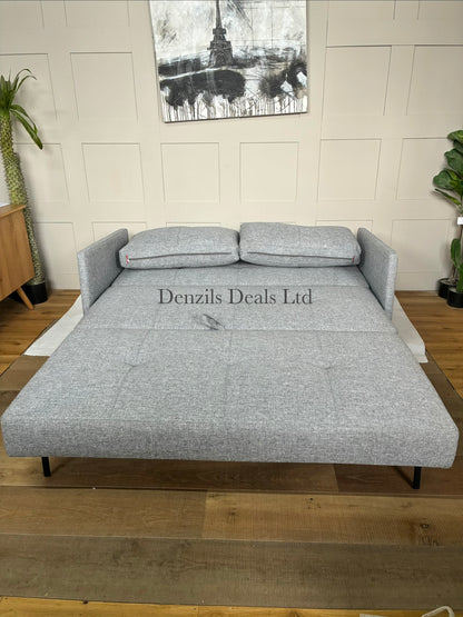 A contemporary living room featuring the compact Innovation Living Cubed 160 Sofa Bed. The sleek, armless frame is covered in a durable Twist Granite grey fabric and elevated by slim black legs, styled with two rectangular plush back cushions.