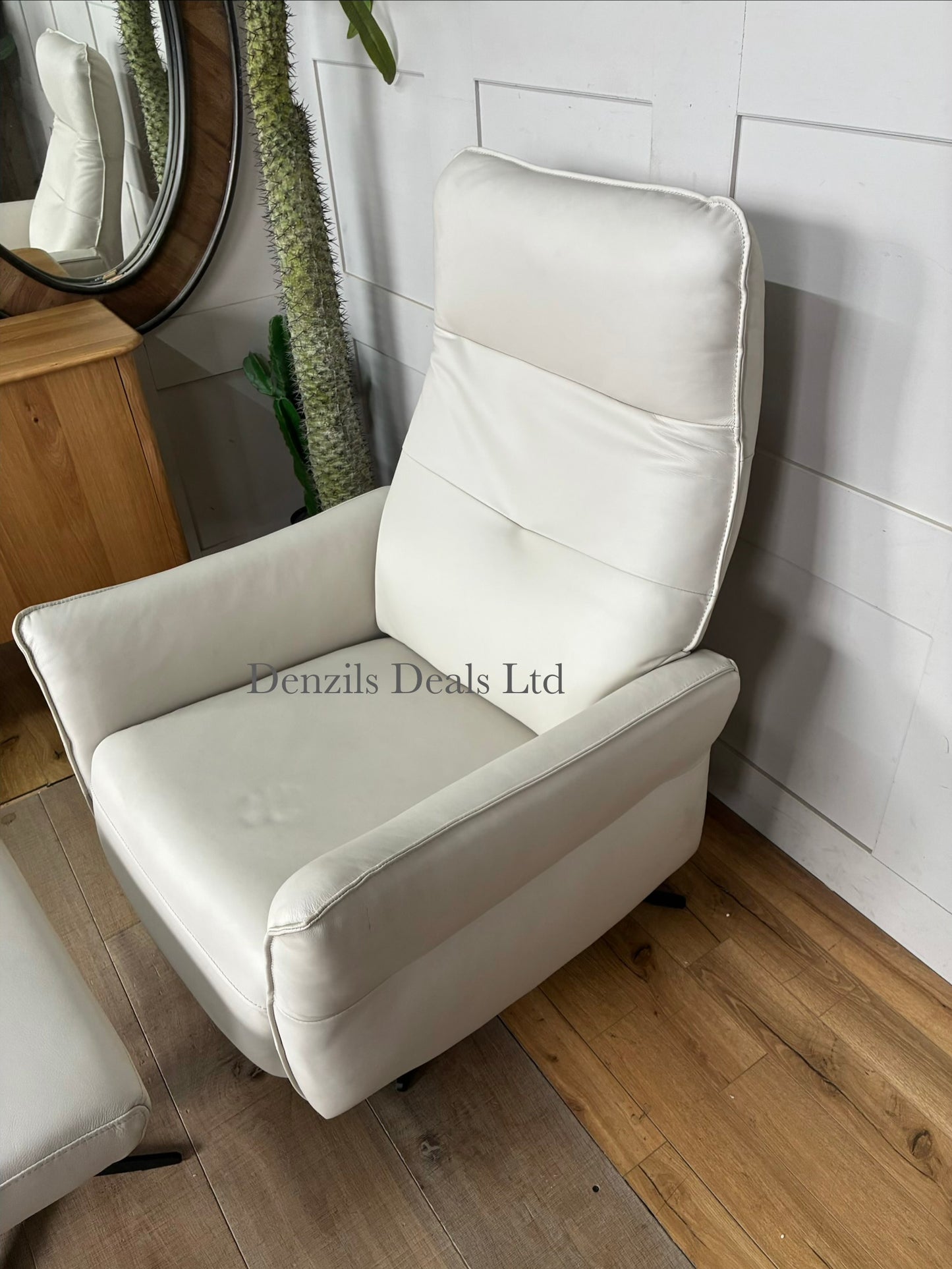 A contemporary living room reclining armchair paired with a matching rectangular footstool. Both pieces are covered in high-quality natural leather, showcasing unique organic textures, wrinkles, and characteristics. The set features a streamlined, padded frame resting on slim, minimalist black metal legs.