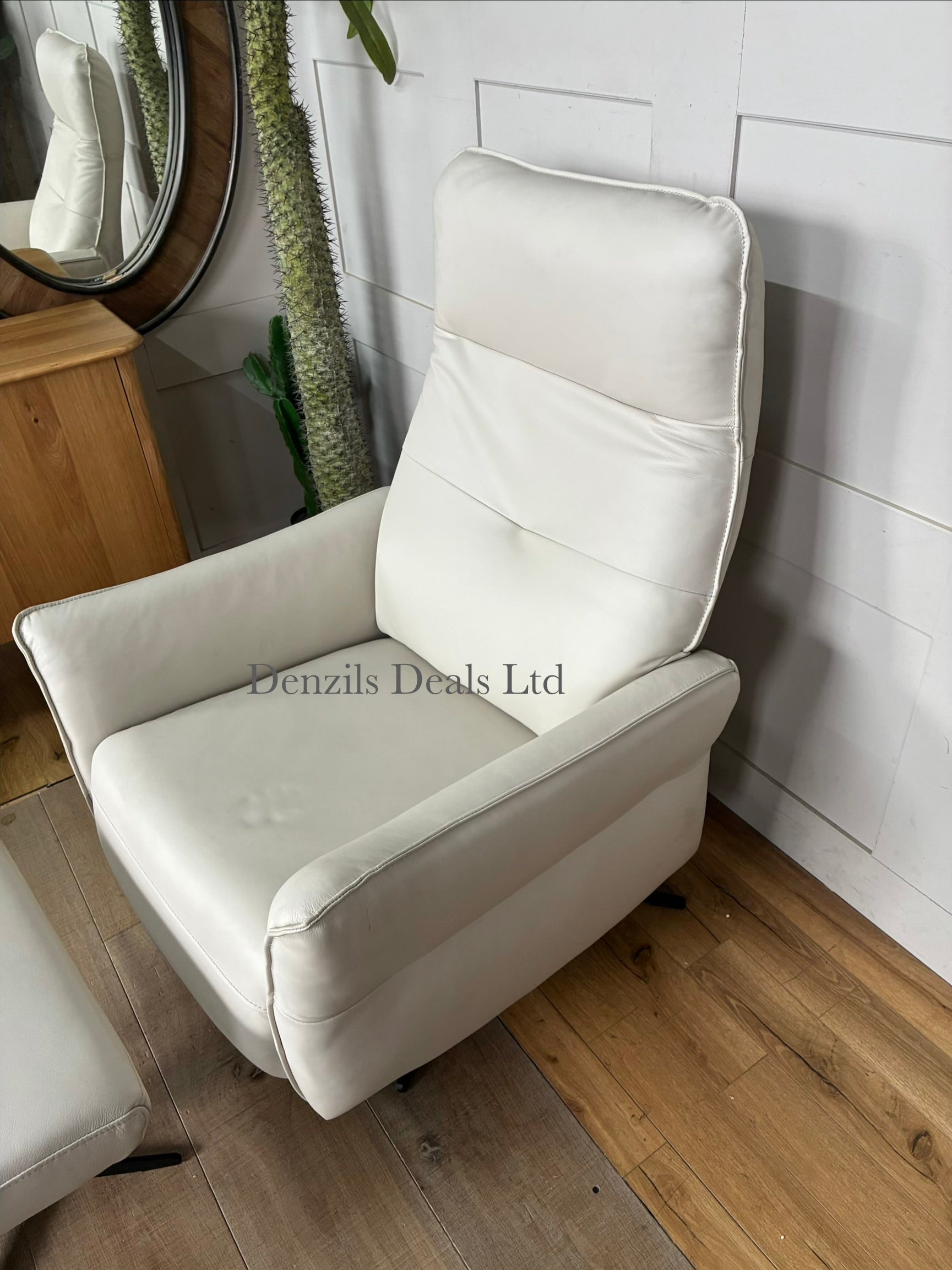 A contemporary living room reclining armchair paired with a matching rectangular footstool. Both pieces are covered in high-quality natural leather, showcasing unique organic textures, wrinkles, and characteristics. The set features a streamlined, padded frame resting on slim, minimalist black metal legs.
