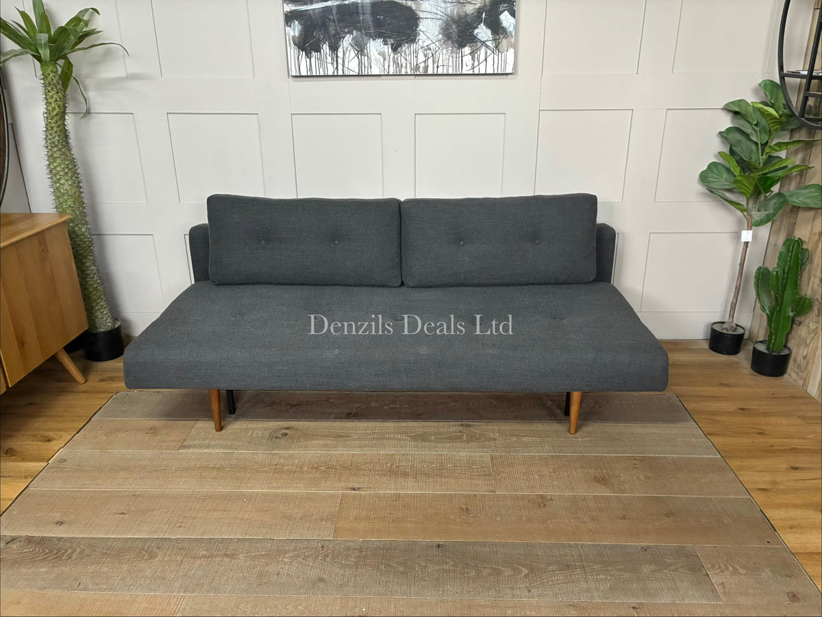 A contemporary mid-century modern style sofa bed by Innovation Living. It features a tailored fabric upholstered seat and backrest with classic button-tufted detailing, two matching rectangular back cushions, and a matte black steel frame supported by tapered, dark stained wood legs.