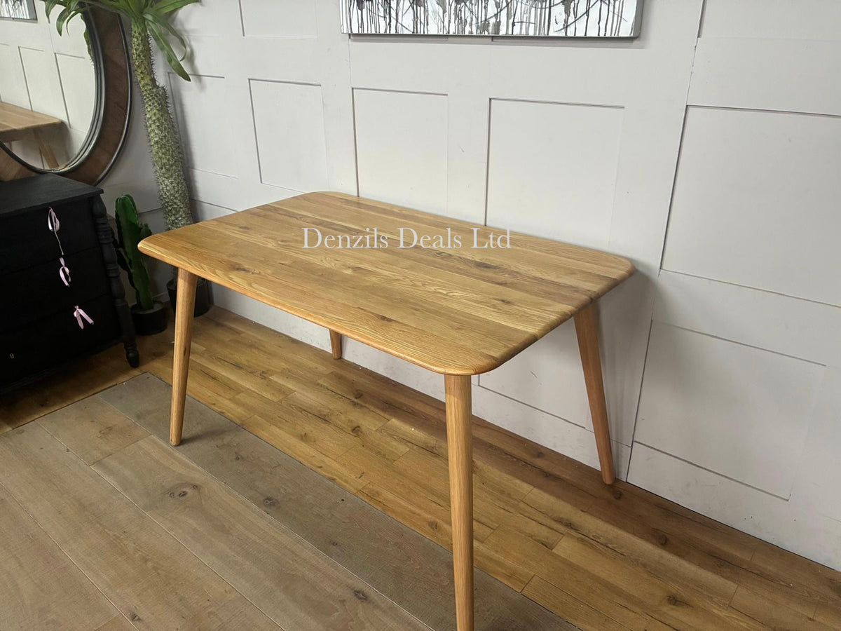 A contemporary rectangular dining table from the John Lewis Greenwood collection. The table is made of solid oak and premium veneers with a smooth Bianco oil clear coat. It highlights a minimalistic mid-century design with subtly tapered legs and a natural, light wood finish