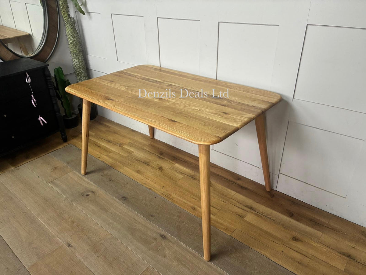 A contemporary rectangular dining table from the John Lewis Greenwood collection. The table is made of solid oak and premium veneers with a smooth Bianco oil clear coat. It highlights a minimalistic mid-century design with subtly tapered legs and a natural, light wood finish