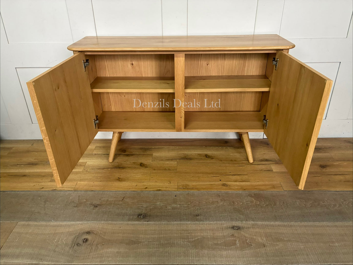 A contemporary two-door wooden sideboard from the John Lewis Greenwood range. The cabinet is crafted from light-toned solid oak and oak veneers, featuring a pale Bianco oiled finish that highlights the natural, linear wood grain. It has a clean, minimalist rectangular shape, flat-fronted double doors with subtle integrated handles, and sits flat against the floor.
