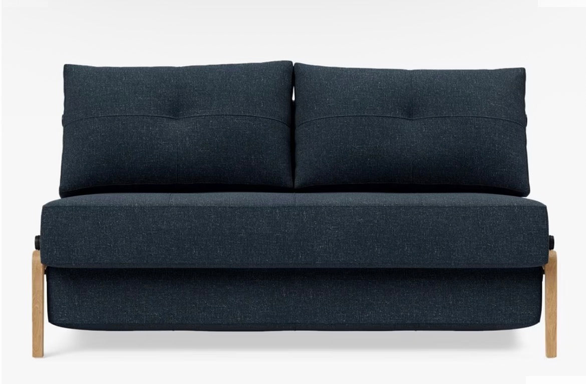 A contemporary two-seater sofa bed from Innovation Living upholstered in a textured, deep Nist Blue 515 fabric, featuring a compact space-saving design with minimalist legs and a clean, modern silhouette.