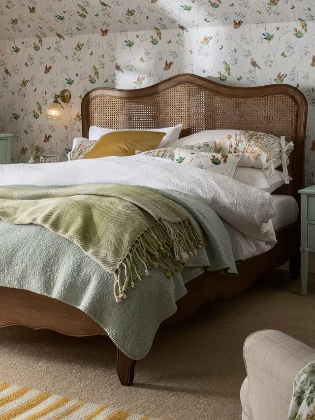 A double-sized Laura Ashley Montpellier bed frame crafted from rich walnut wood, showcasing a high arched headboard with an intricate woven rattan panel, curved French-inspired legs, and profiled side rails.