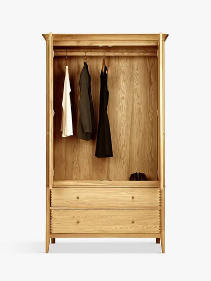 A freestanding double wardrobe made of light natural oak, featuring two paneled doors, smooth rounded edges, and two wide storage drawers at the base with small metal handles.