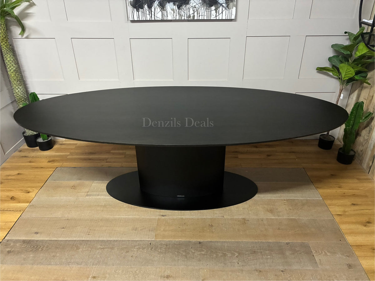 A large 250cm contemporary rectangular dining table by Richmond Interiors. The tabletop is crafted from oak and oak veneer with a dark coffee brown finish that subtly shows the natural wood grain. It is supported by a heavy-duty, modern black iron central pedestal base.