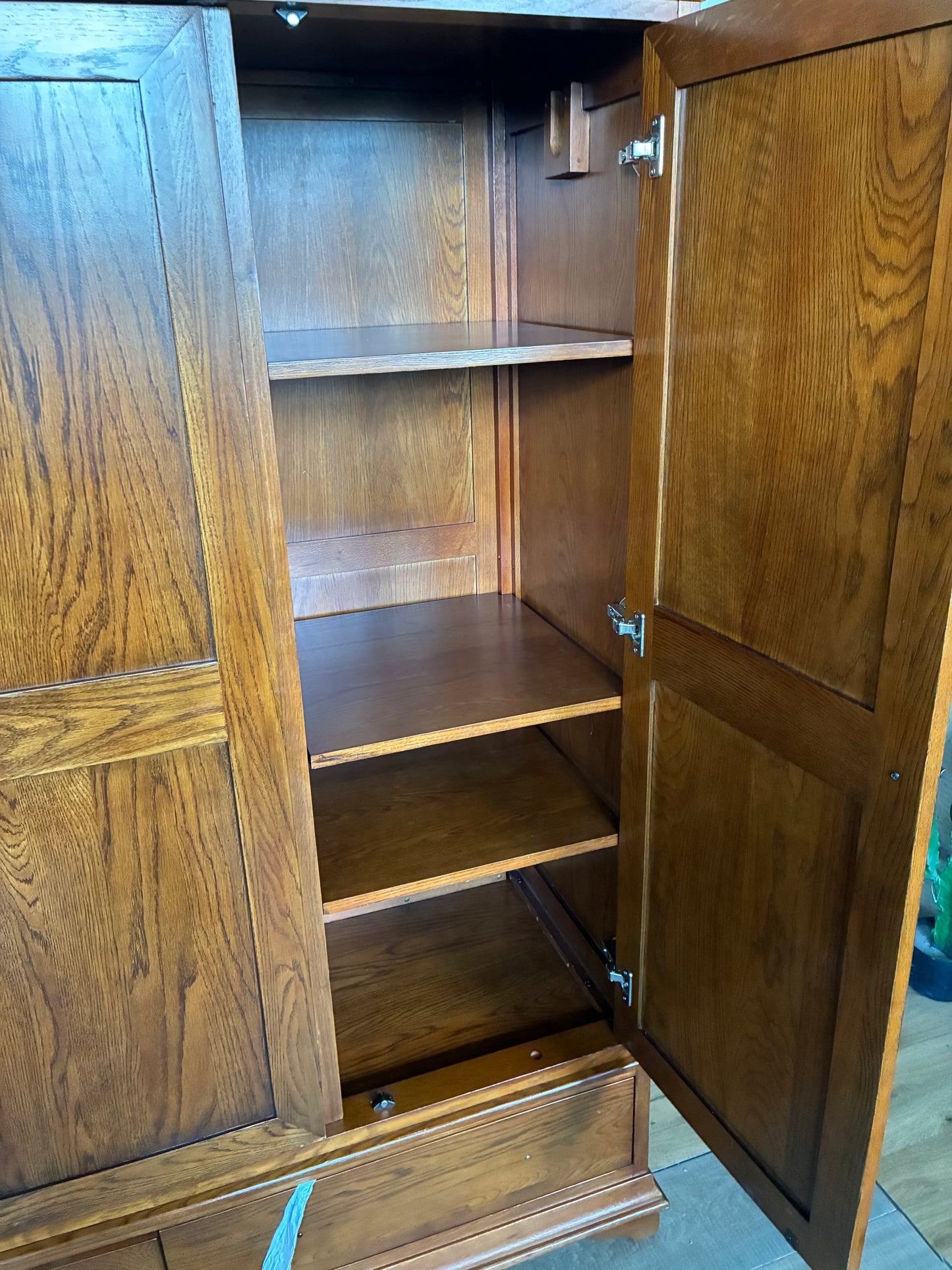 A large The Cotswold Company Winchcombe Dark Oak Triple Wardrobe styled in a master bedroom. The heavy, dark-stained oak structure showcases a prominent natural wood grain, matching traditional Georgian-inspired woodwork, and stands alongside warm, classic home decor.