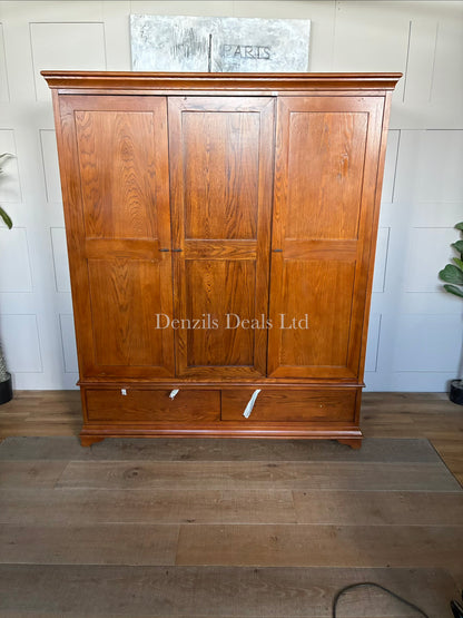A large, three-door Winchcombe Dark Oak Triple Wardrobe by The Cotswold Company, featuring a traditional rich dark brown wood grain finish, an elegantly curved bow-front profile, delicate top cornicing, and antiqued metal handles on the doors above two deep base drawers.