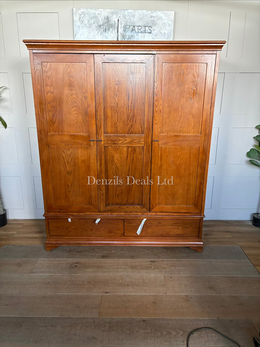 A large, three-door Winchcombe Dark Oak Triple Wardrobe by The Cotswold Company, featuring a traditional rich dark brown wood grain finish, an elegantly curved bow-front profile, delicate top cornicing, and antiqued metal handles on the doors above two deep base drawers.
