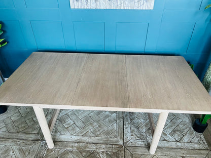 A light-coloured white oak extendable dining table featuring a minimalist, modern farmhouse silhouette. The table has soft, subtly rounded edges on its rectangular top and is supported by four straight, rectangular legs with a matching wooden support beam running underneath.