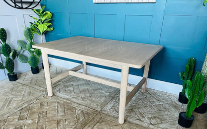 A light-coloured white oak extendable dining table featuring a minimalist, modern farmhouse silhouette. The table has soft, subtly rounded edges on its rectangular top and is supported by four straight, rectangular legs with a matching wooden support beam running underneath.
