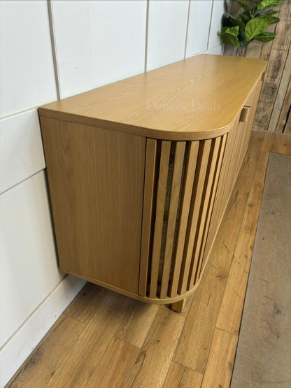 A light oak wood capsule-shaped TV stand with vertical slatted doors and minimalist wooden handles.