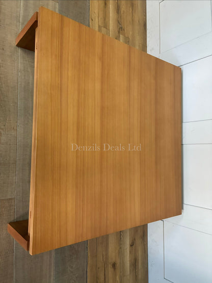 A low-profile, square West Elm Ainsley wooden coffee table in a nutmeg finish, styled in the center of a modern living room seating arrangement.