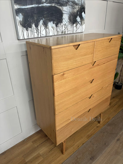A medium-sized chest of drawers made from natural oak wood with three wide drawers and integrated handle-less design. It sits on four elegantly curved legs, showcasing a warm wood grain and a modern, minimalist silhouette.