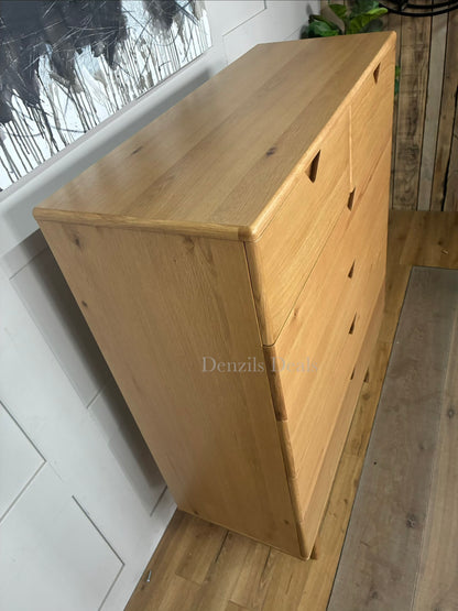 A medium-sized chest of drawers made from natural oak wood with three wide drawers and integrated handle-less design. It sits on four elegantly curved legs, showcasing a warm wood grain and a modern, minimalist silhouette.