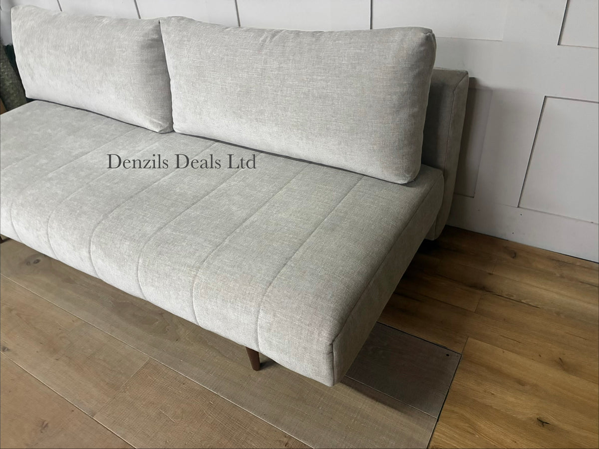 A minimalist Innovation Living Ripple sofa bed folded out into a 140x200 cm double bed. The smooth Avella Sand beige fabric covers a pocket sprung mattress, supported by a metal frame and discrete wooden legs