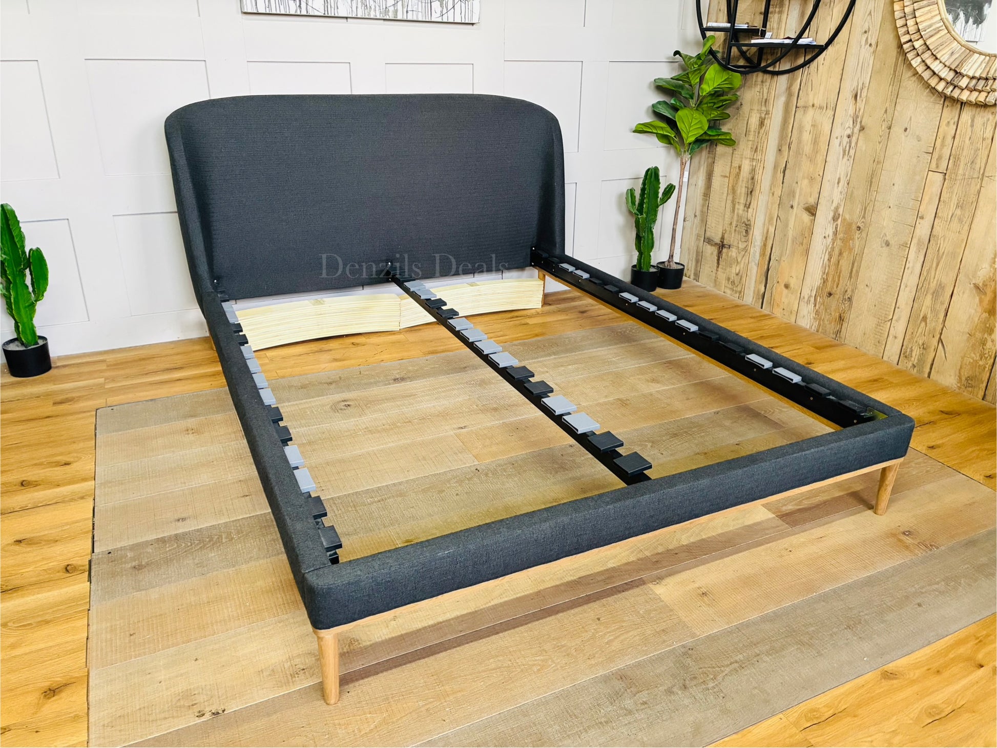 A modern John Lewis Show-Wood King Size Bed Frame covered in a cozy, textured brushed tweed charcoal fabric with a soft herringbone pattern. The bed features a gently curved, padded headboard and a sleek, exposed light wood frame running along the bottom and legs