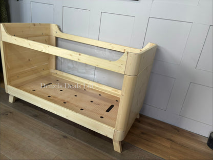A modern Scandinavian-style SAZY baby cot bed made from natural spruce wood, featuring clear, transparent acrylic sides for full visibility.