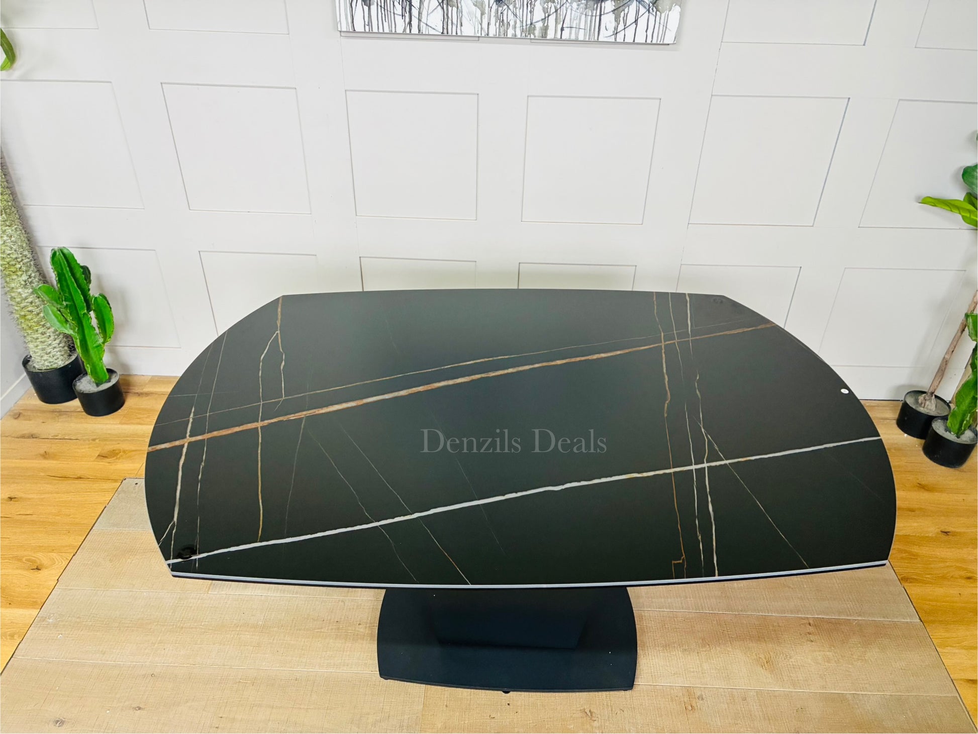 A modern black ceramic dining table with a distinctive white-veined marble effect. The table features an extendable top and a sleek, curved fiberglass tulip-style pedestal base. 