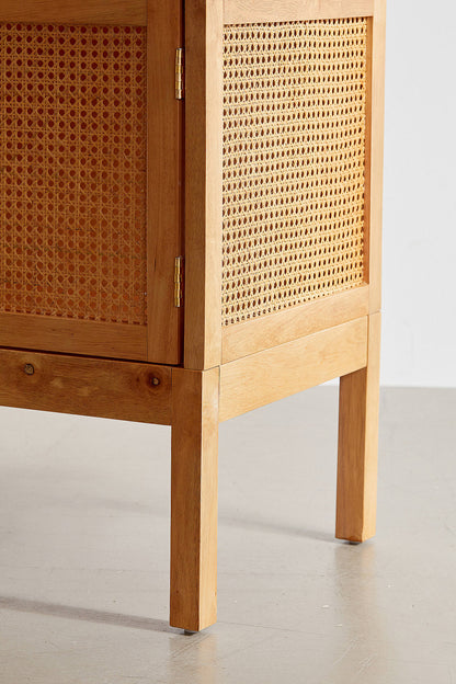 A modern bohemian TV stand made of light wood veneer and cane rattan panels. It features two cabinet doors with woven rattan fronts, small block handles, and tall, slim tapered legs