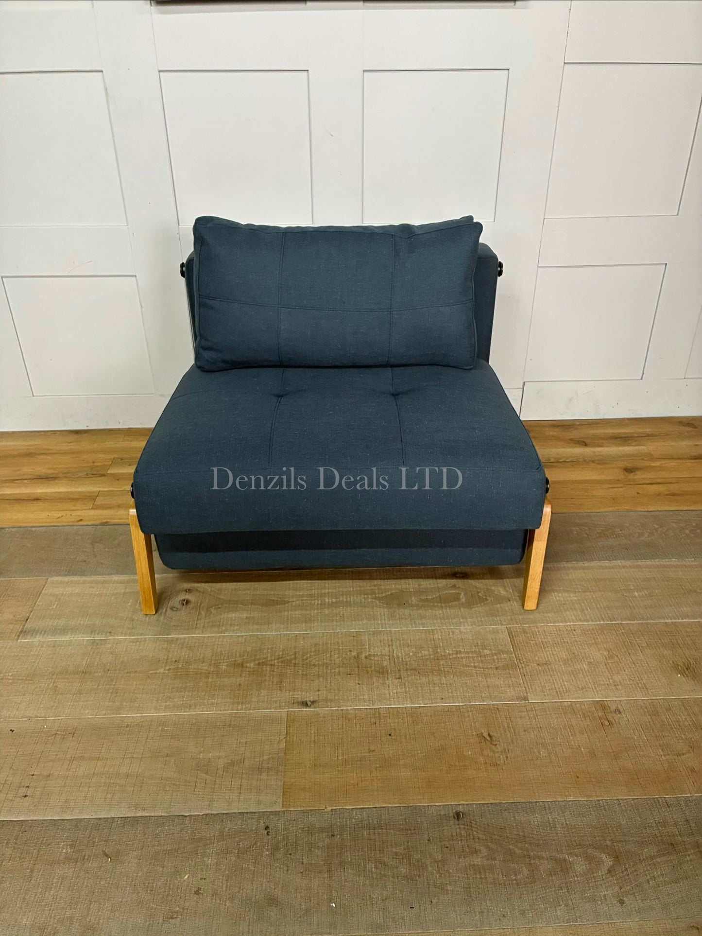 A modern compact armchair upholstered in textured Nist Blue fabric by innovation living with a slightly inclined seat and clean armrests,