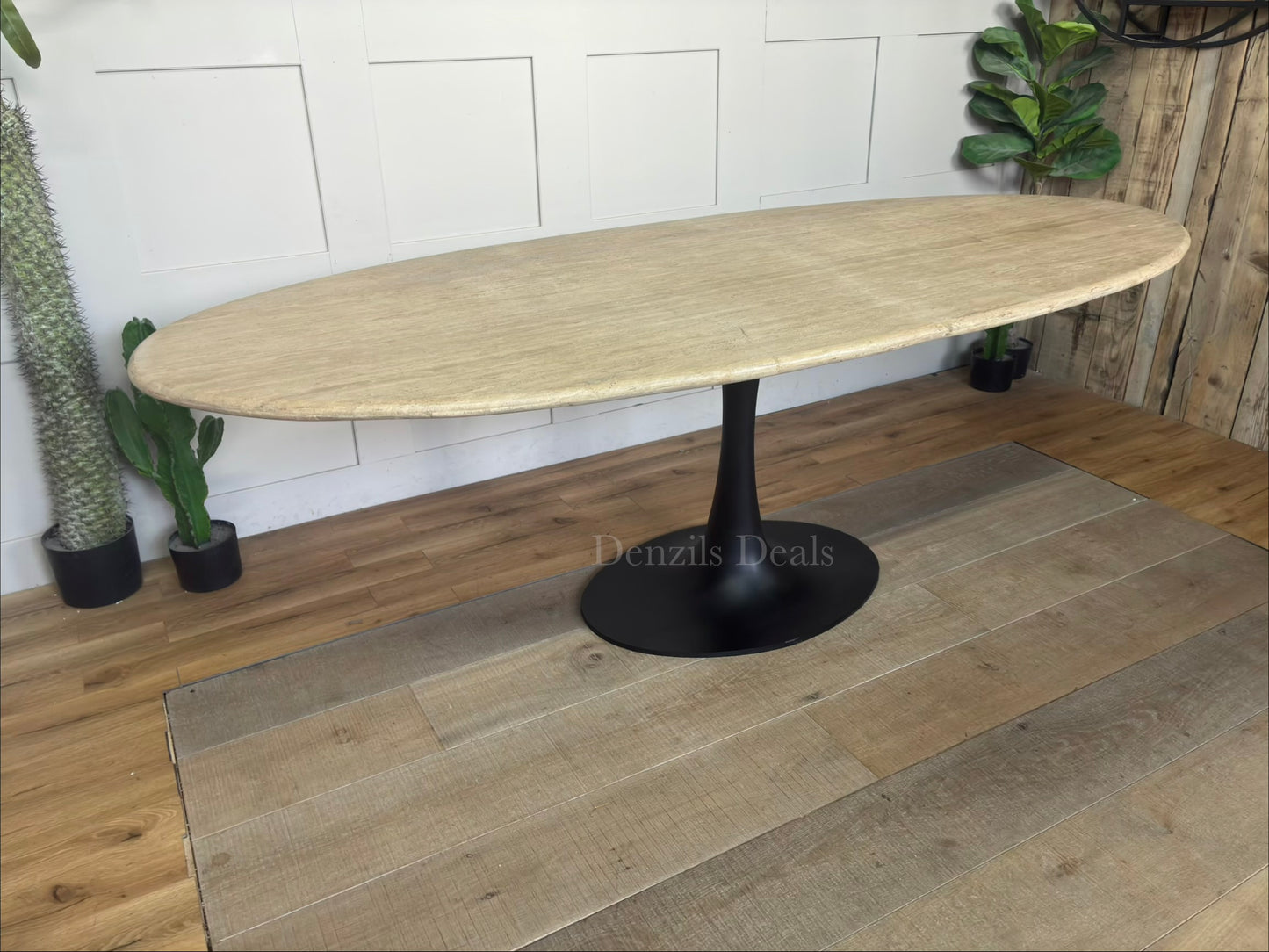 A modern dining room table by Richmond Interiors from the Hampton collection, featuring a large oval beige travertine tabletop with unique natural veining, supported by a sleek, black powder-coated iron base