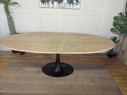 A modern dining room table by Richmond Interiors from the Hampton collection, featuring a large oval beige travertine tabletop with unique natural veining, supported by a sleek, black powder-coated iron base