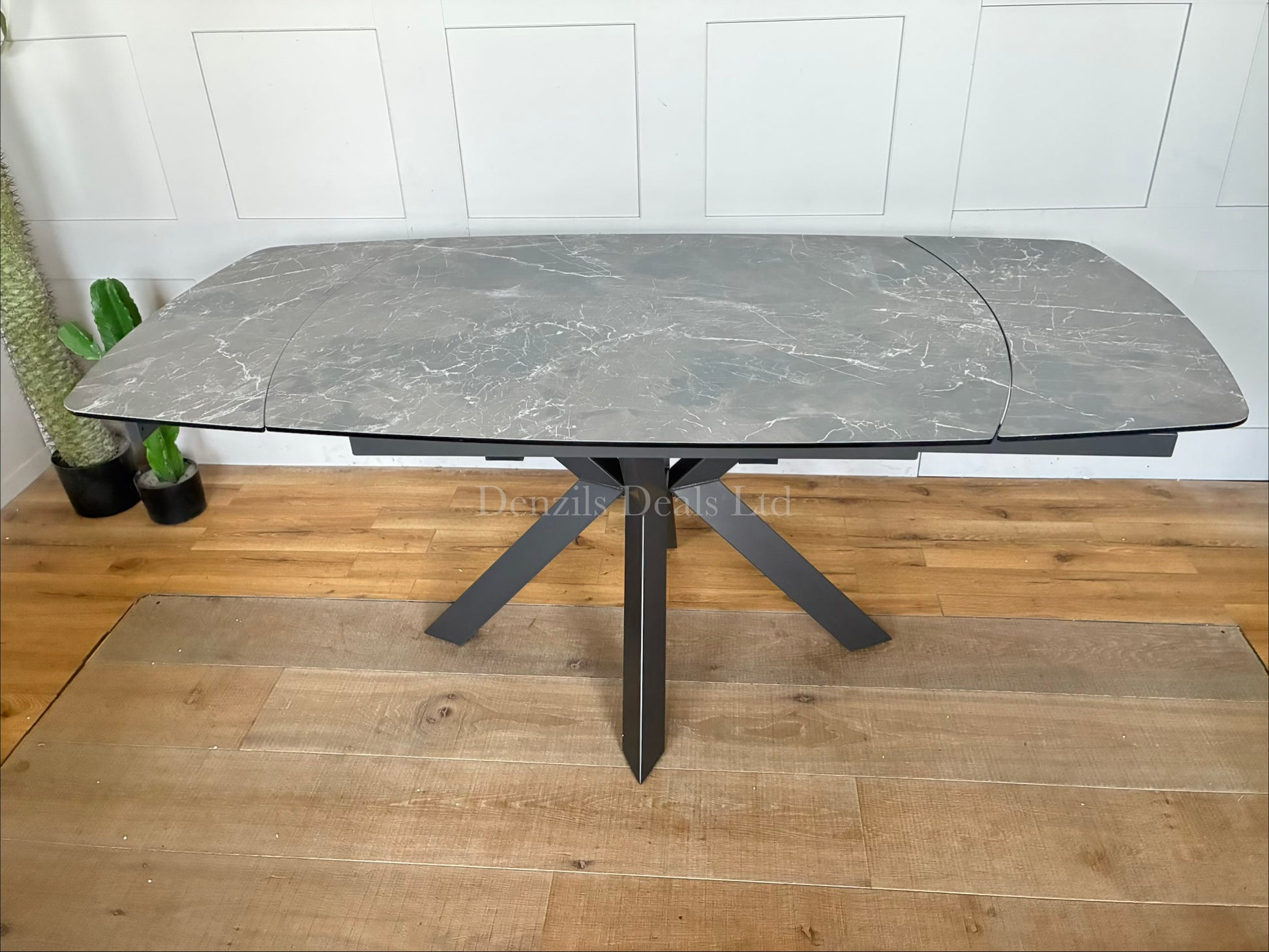 A modern rectangular extending dining table featuring a sleek printed glass top with an HPL finish and a smooth twist-to-open central extension mechanism, supported by a contemporary matte metal base."
