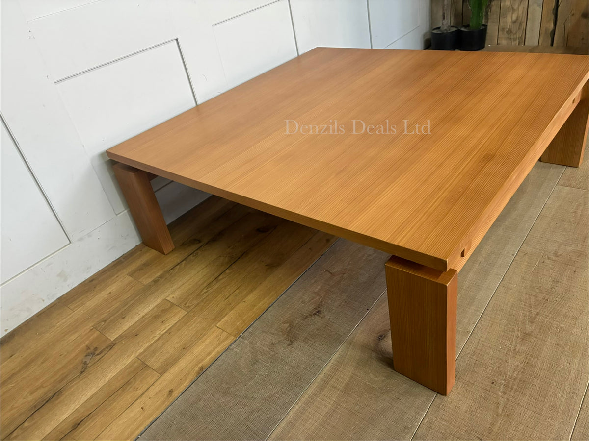 A modern square wooden coffee table featuring a low profile, clean straight lines, and a warm nutmeg finish.