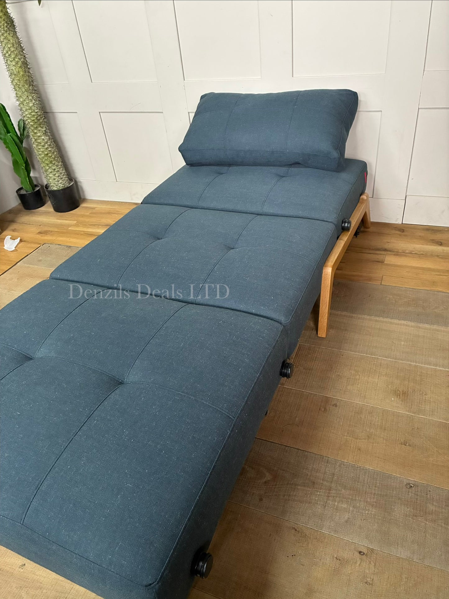 "A modular Innovation Living Cubed 90 armchair shown in a deep Nist Blue shade. The compact armchair folds out seamlessly from a stylish single seat into a flat, supportive twin-sized sleeper bed for guests."
