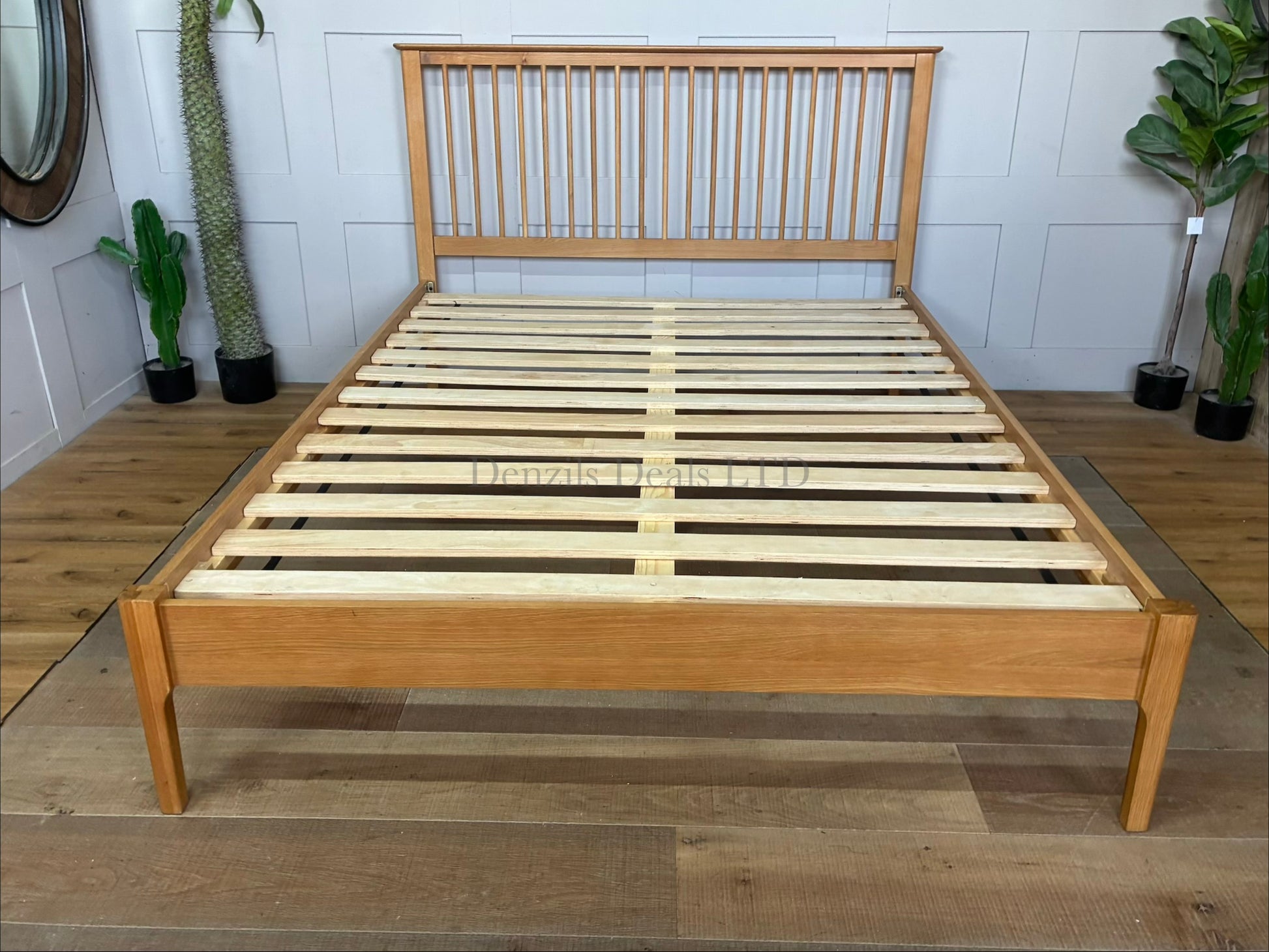 A natural solid oak and oak veneer king-size bed frame featuring a traditional Shaker-style panelled headboard with vertical spindles, clean horizontal lines, tapered wooden legs, and a low foot end showcasing a warm natural wood grain finish
