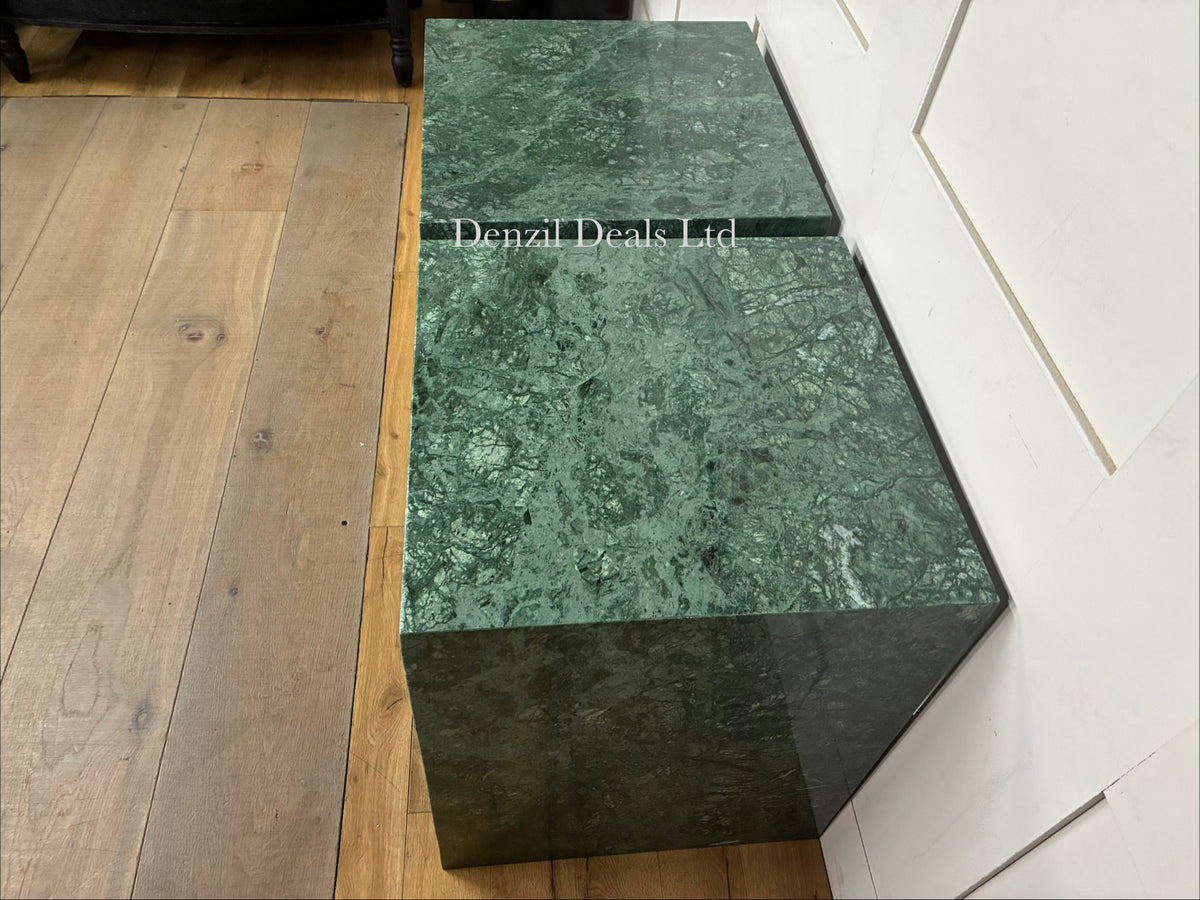 A pair of modern side tables crafted from smooth, solid green marble with natural white veining, featuring an open, minimalist structural silhouette and a polished finish