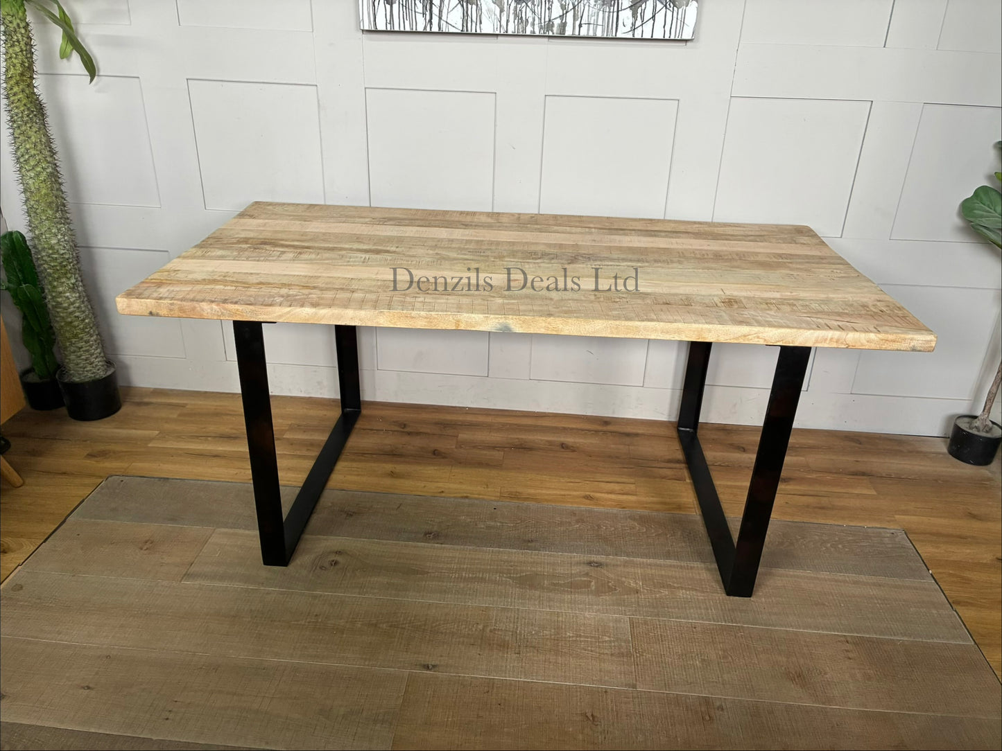 A rectangular 6-seater dining table showcasing a thick, natural mango wood top with prominent organic grain patterns, supported by a strong black industrial-style angular iron base